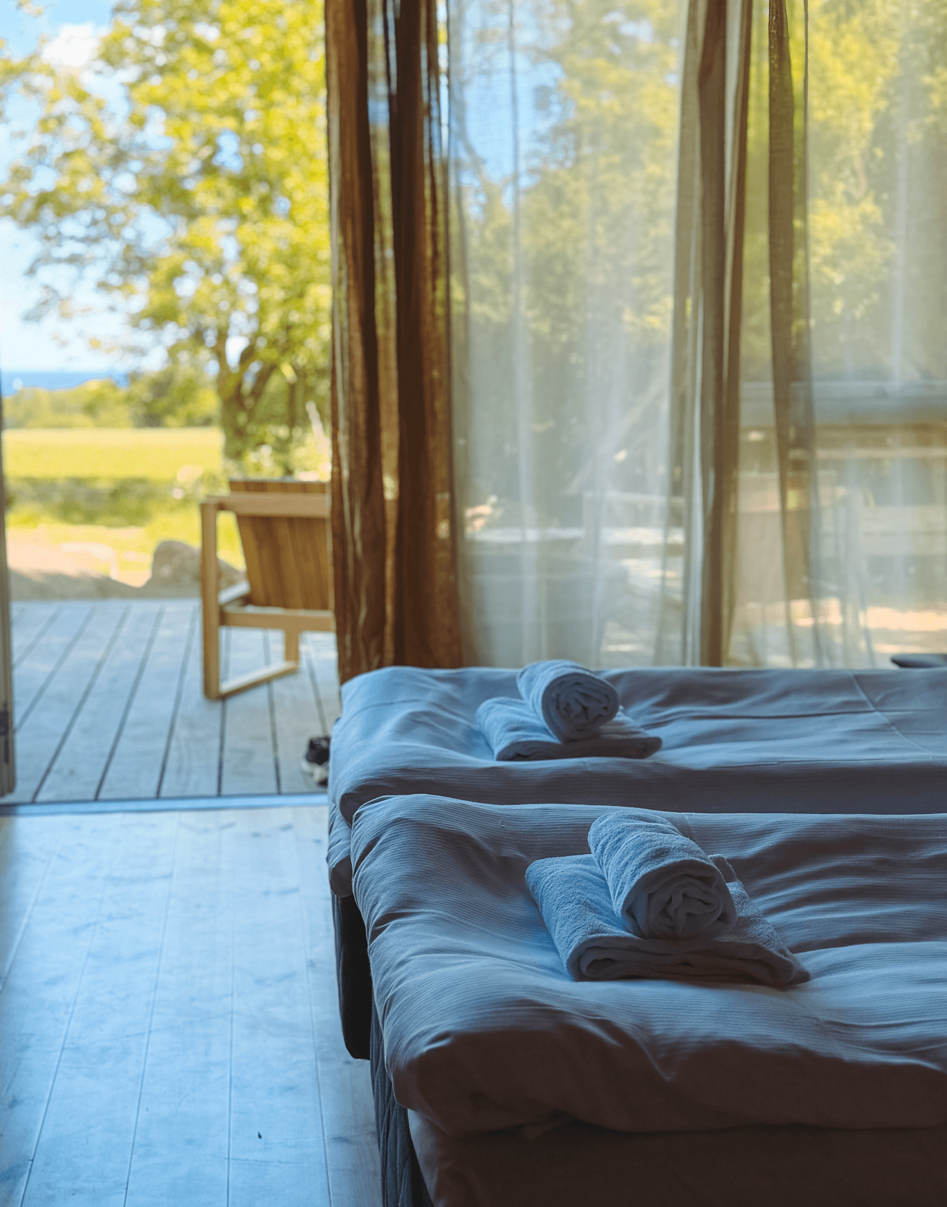 Udsigt fra værelset over mark og hav på Bornholm med terrasse og opredte senge